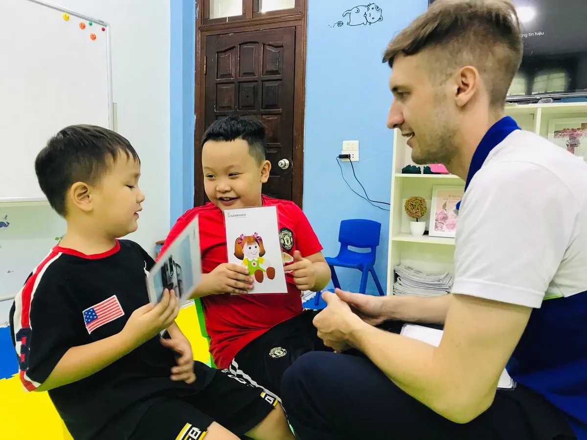 A native teacher and young learners with a picture book in class